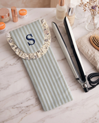 Funda para plancha de pelo en rayas azul cielo y caqui con volante de flores en la solapa. Cierra con velcro. BanoffeeBCN