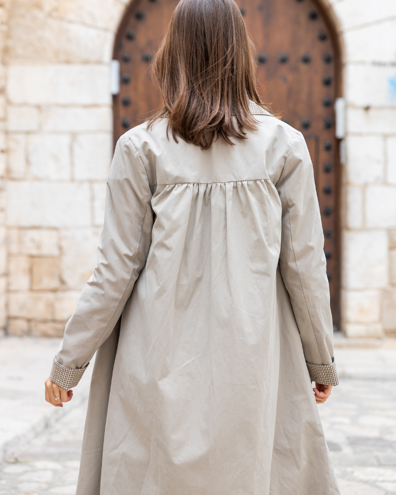 Gabardina Copenhagen color beige combinada con camisa, pantalón de rayas y bolso.