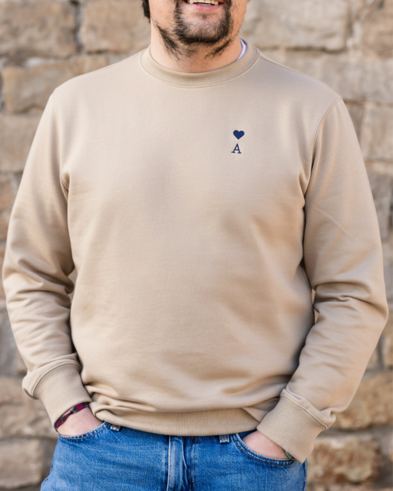 Sudadera personalizada beige con inicial y corazón bordado llevada por modelo en look casual