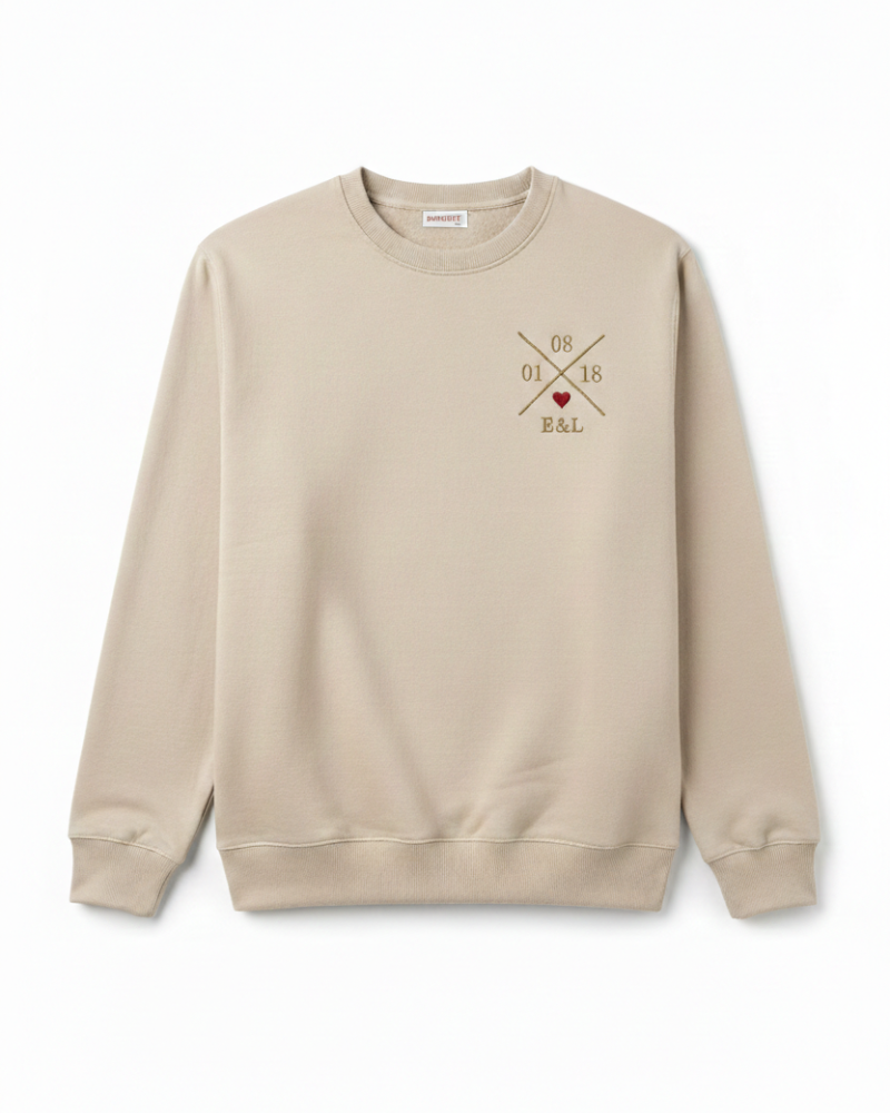 Sudadera beige unisex vista frontal, con X bordada personalizada y corazón granate en pecho izquierdo