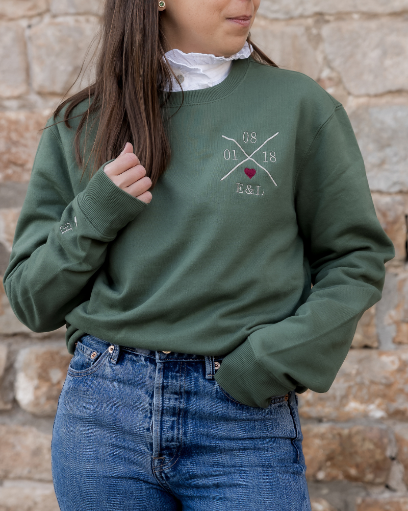 Modelo vistiendo sudadera verde caqui unisex, vista frontal, personalizada y corazón granate bordado en pecho izquierdo