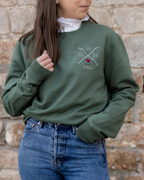 Modelo vistiendo sudadera verde caqui unisex, vista frontal, personalizada y corazón granate bordado en pecho izquierdo