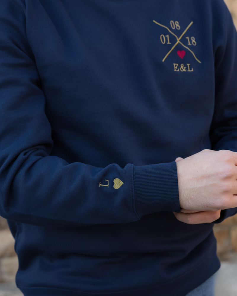 Modelo vistiendo sudadera azul marino unisex, vista lateral derecha, bordado de inicial y corazón visible